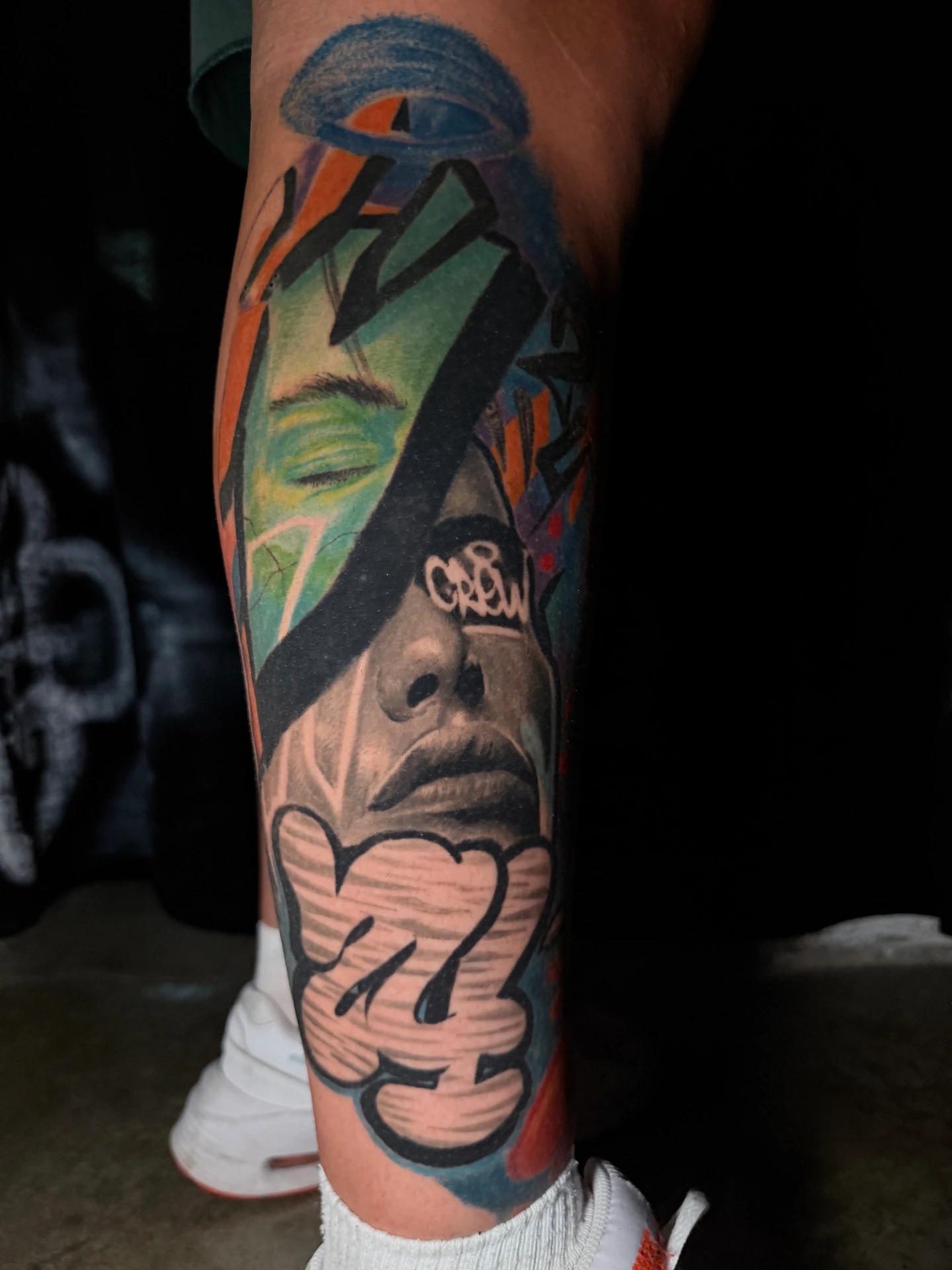 Tatuaje a color con retrato realista y graffiti urbano realizado por Santana Art