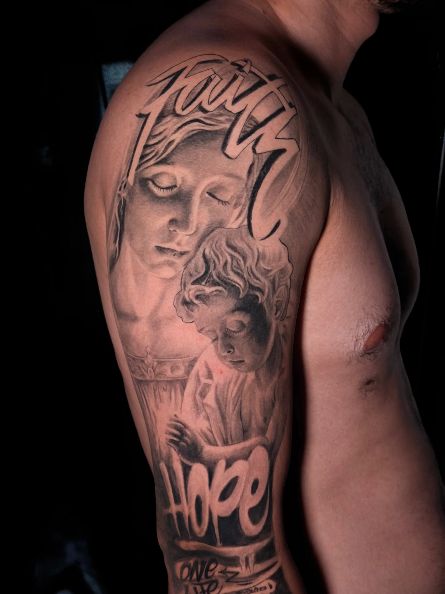 Tatuaje 'Faith' en brazo, retrato realista black and grey con lettering urbano realizado por Santana Art